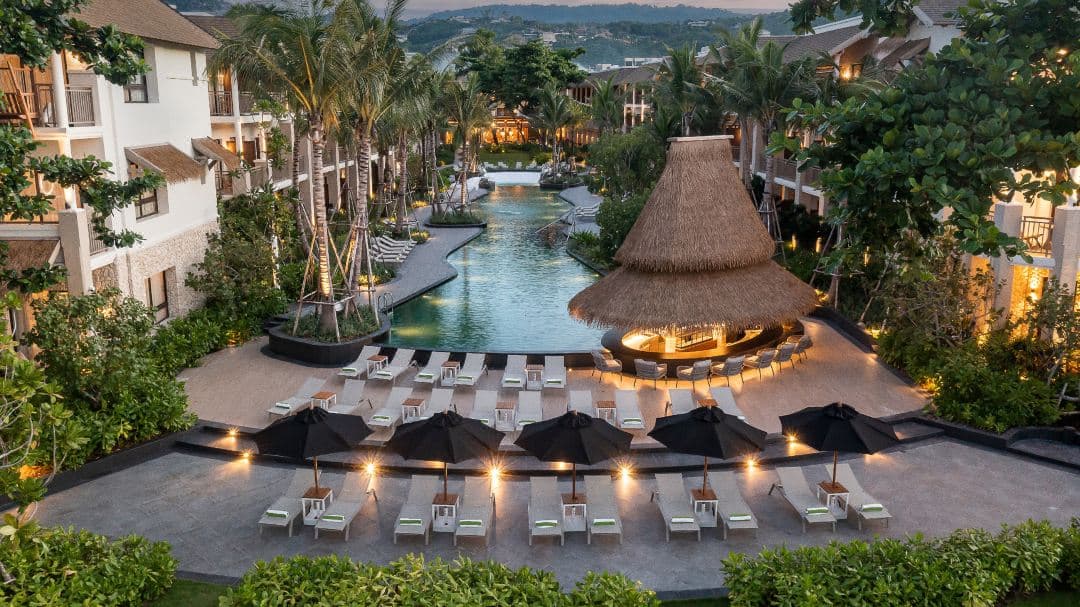 Modern open-air lobby at Holiday Inn Samui featuring a large Java Plum tree growing through a circular roof opening.