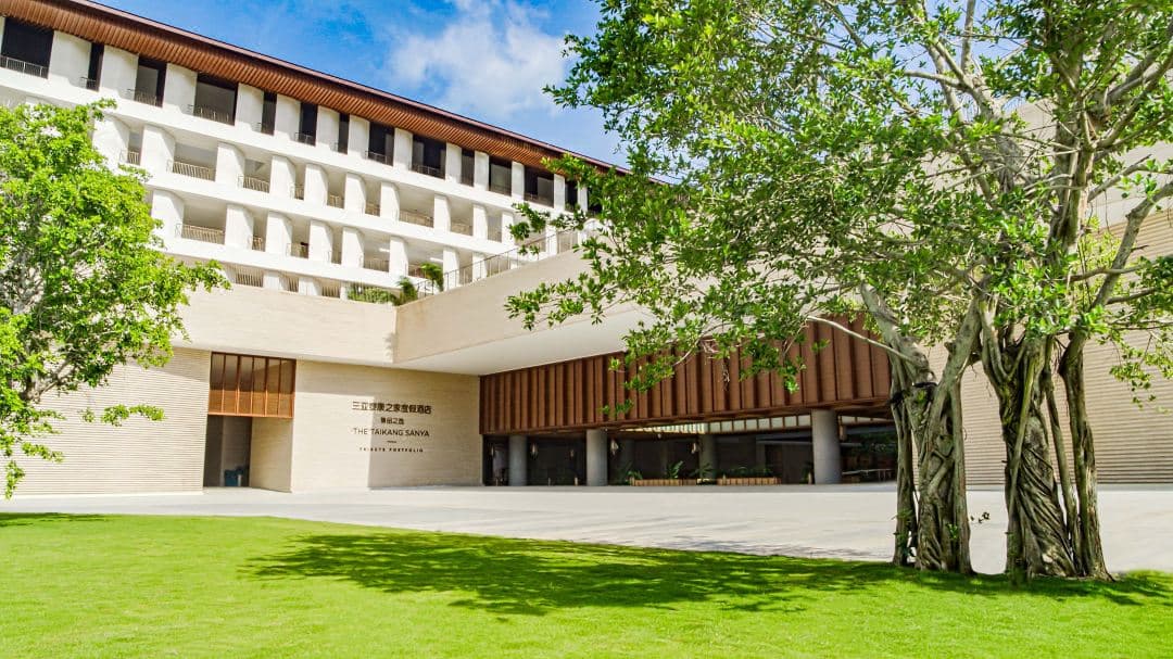 The central water courtyard at The Taikang Sanya, featuring a symmetric reflection of the Neri&Hu designed 'Walled City' architecture and bamboo corridors.