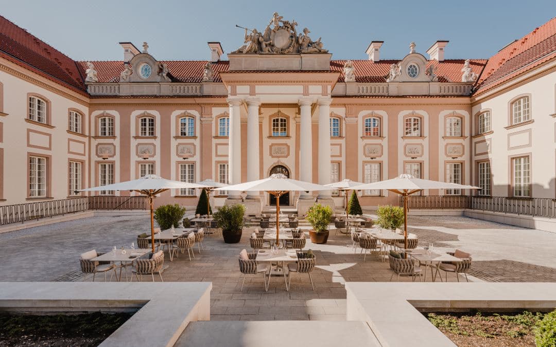 The glass-walled Pawilon restaurant at Hotel Verte, juxtaposed against the historic Baroque facade of the Branicki Palace.