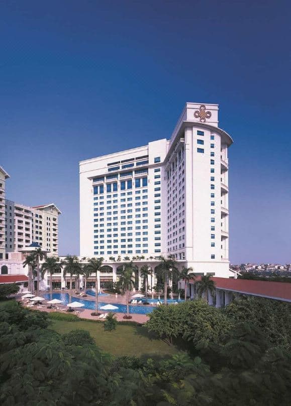 The massive serpentine outdoor pool of Hanoi Daewoo Hotel reflecting the curved white facade and palm trees.