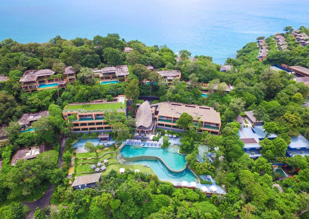 A stunning dusk view of Baba Nest rooftop bar at Sri panwa Phuket, featuring a wrap-around infinity pool, low seating, and guests enjoying cocktails against a 360-degree Andaman Sea backdrop.