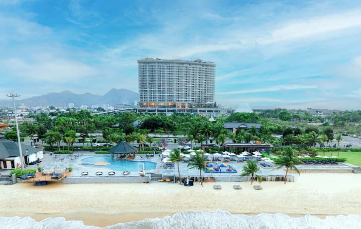 A panoramic view of the Da Nang Mikazuki infinity pool at sunset, overlooking the bay with the massive Mount Fuji replica in the background.