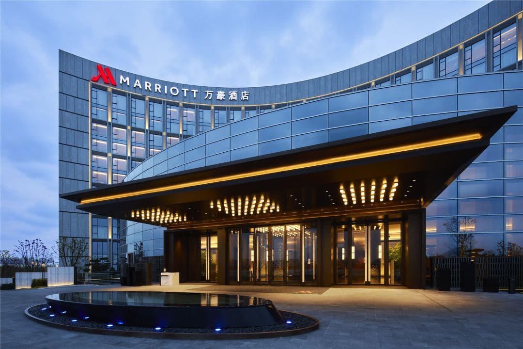 A sleek, modern hotel lobby featuring 13-meter high artistic 'Sail' screens and warm ambient lighting.