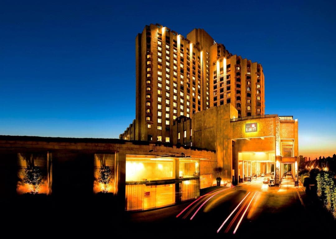 The grand lobby of The LaLiT New Delhi featuring massive art installations and a sweeping staircase.