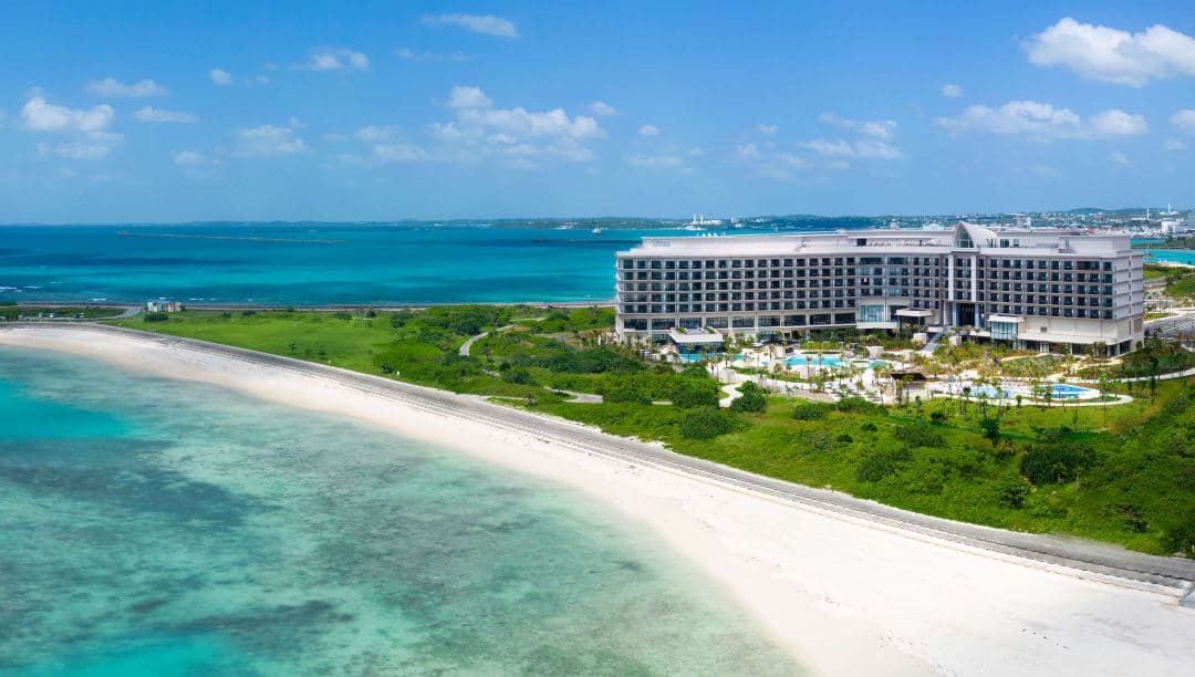 View from Hilton Okinawa Miyako Island Resort balcony overlooking the swimming pools and the Irabu Bridge spanning the vibrant Miyako Blue ocean.