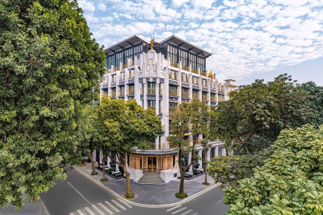 The Hudson Rooms rooftop bar at Capella Hanoi featuring Art Deco design, velvet seating, and a view of the Hanoi skyline.