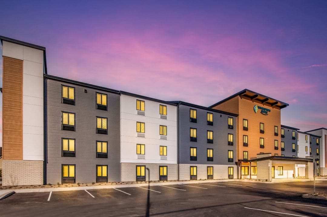 The zigzag terracotta facade of Cambria Hotel Boston Somerville glowing at twilight, framing the modern floor-to-ceiling windows.