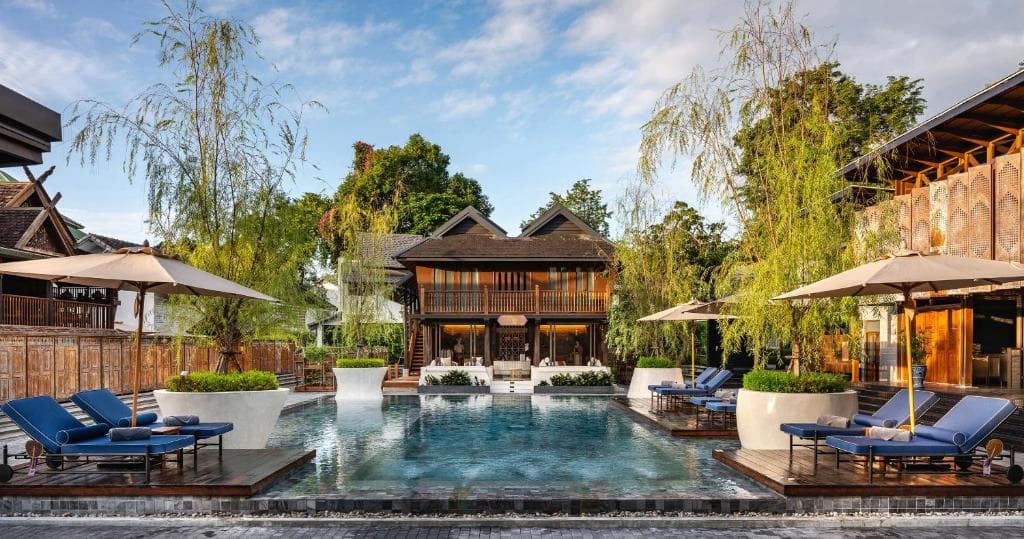 Aleenta Retreat Chiang Mai 修复后的金色柚木 1892 酒吧在暮色中熠熠生辉,俯瞰着中央庭院。