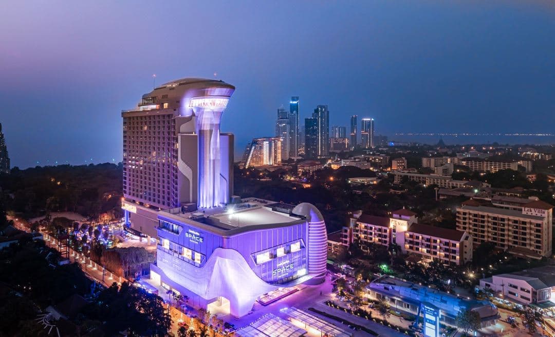 Futuristic kinetic facade of Grande Centre Point Space Pattaya glowing purple at twilight.