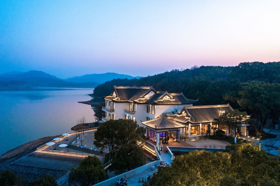 Minimalist wooden facade of Tianmu Lake Yu Biboyuan Hotel framed by lush green mountains and tea plantations.
