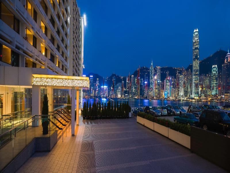 View of Victoria Harbour skyline from a Marco Polo Hongkong Hotel room window at dusk.