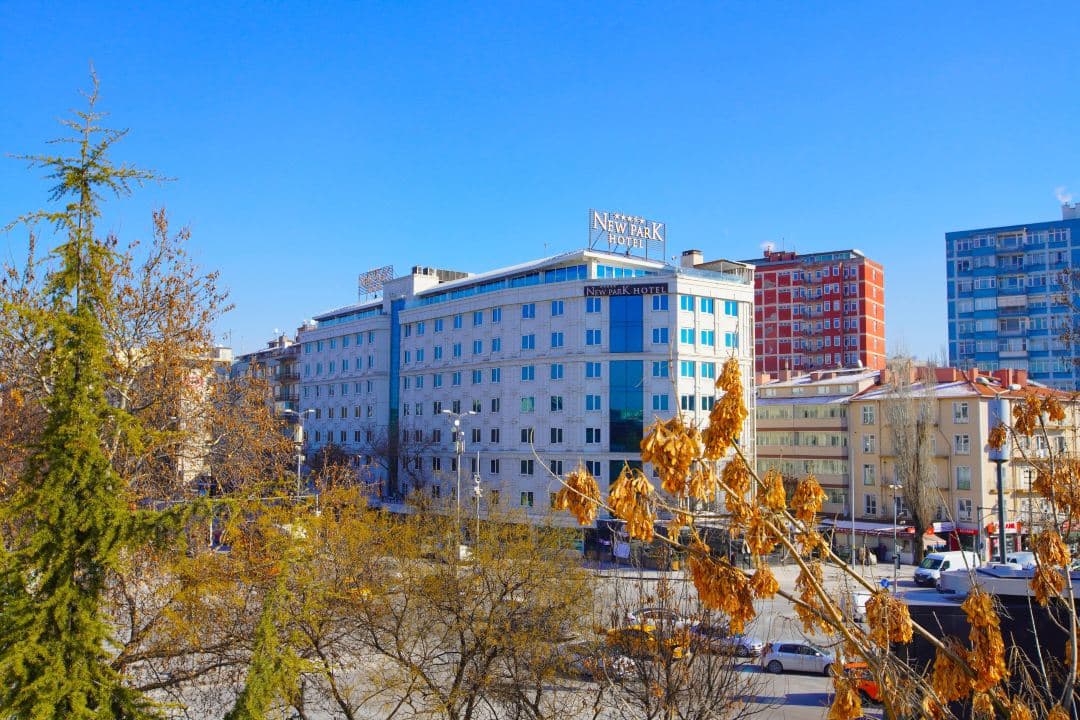 A golden-hour view from the New Park Hotel rooftop terrace overlooking the lush trees of Kurtuluş Park in Ankara.