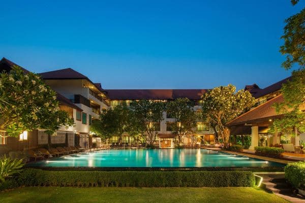 RatiLanna Riverside Spa Resort infinity pool merging with the Mae Ping River at dusk, framed by traditional Lanna architecture.