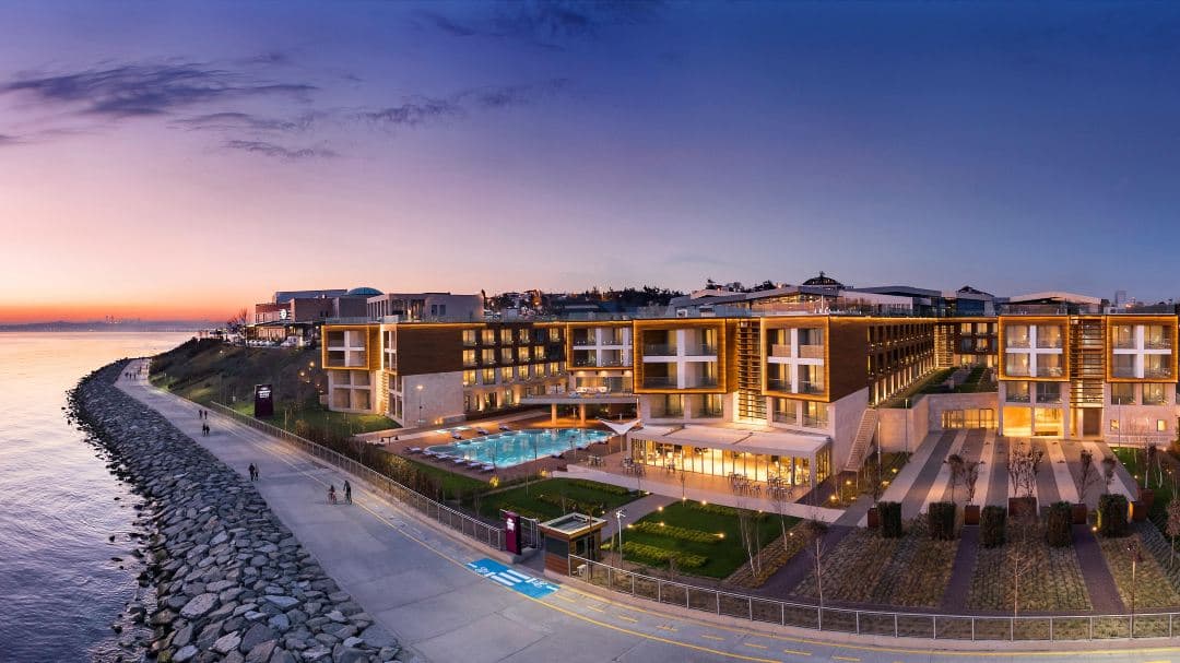 A sunset view from the Atrox Restaurant terrace at Crowne Plaza Florya, overlooking the Sea of Marmara with an outdoor pool in the foreground.