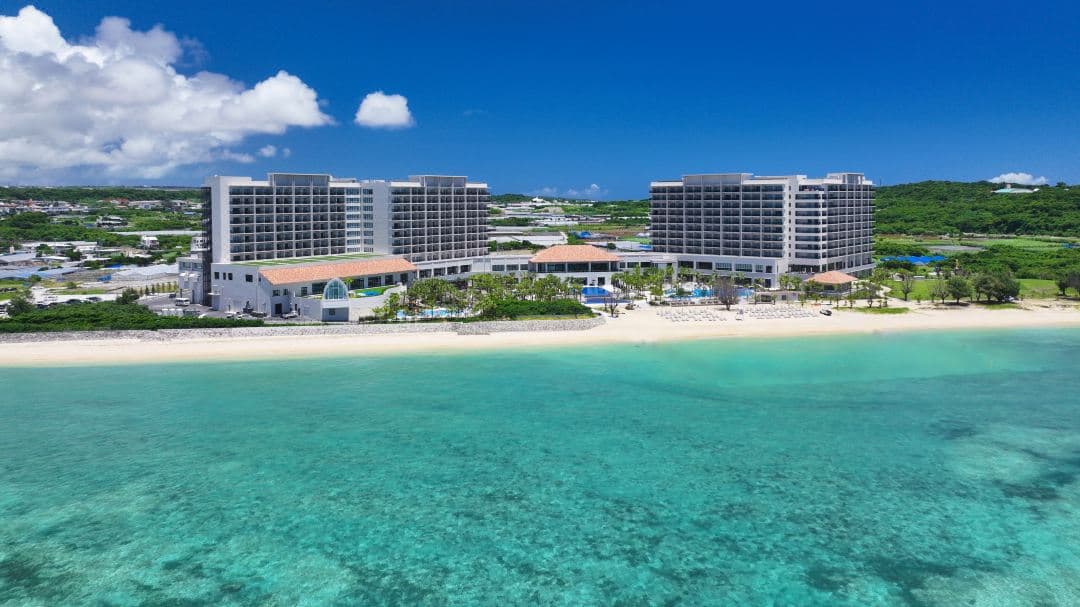 Sunset view over the expansive main pool and chapel at Ryukyu Hotel & Resort Nashiro Beach, with colonial-style architecture in the background.