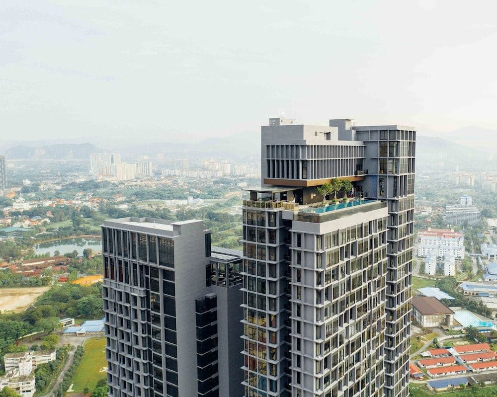 A swimmer at the edge of the Level 48 infinity pool at Expressionz Professional Suites, overlooking the Kuala Lumpur skyline and Petronas Towers at dusk.