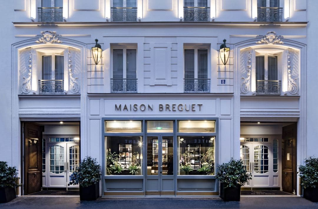 Maison Bréguet 飯店充滿光線的玻璃中庭餐廳,裝飾有懸掛的綠植和工業時尚風格。