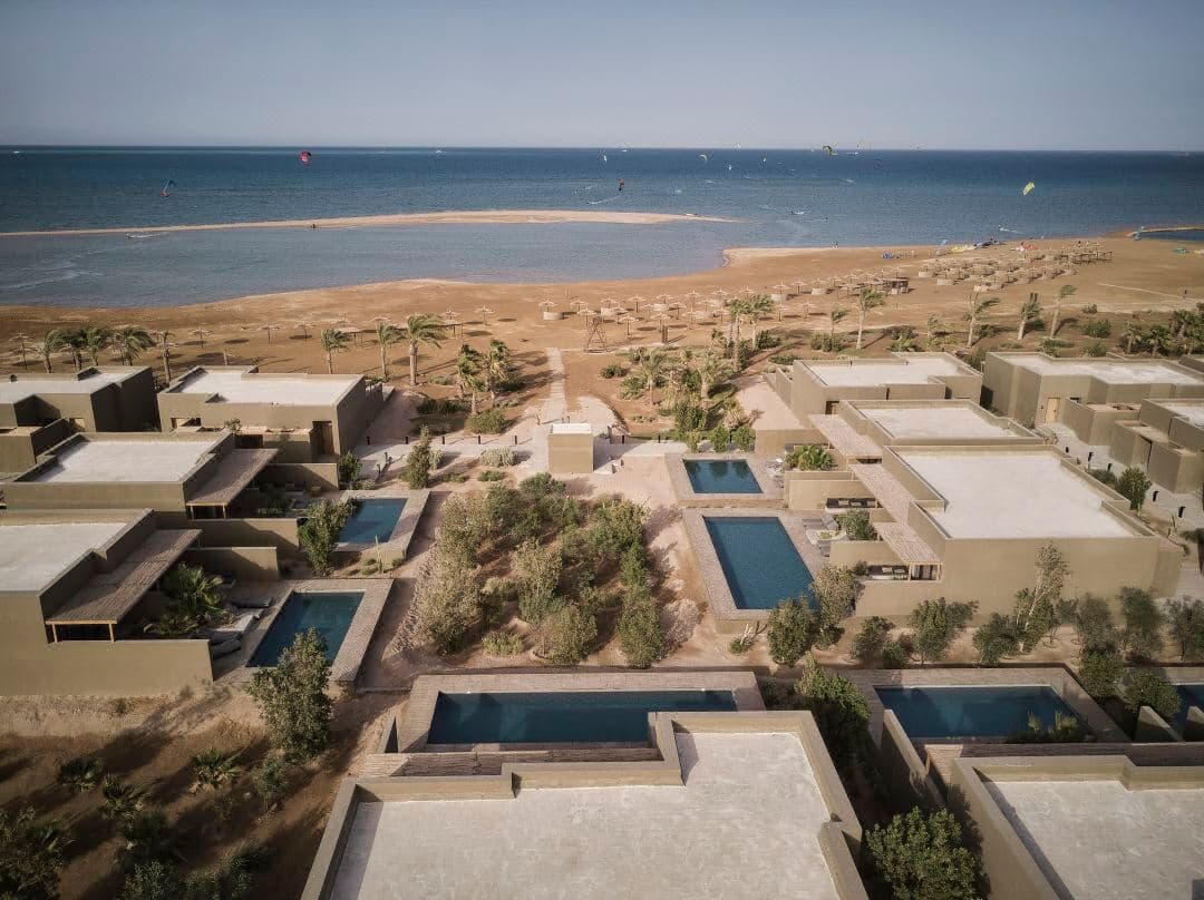A raw concrete villa with a private pool at Casa Cook El Gouna, framed by desert landscaping and rattan furniture.