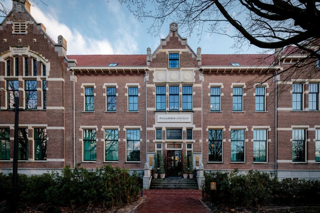High-ceilinged VanOost restaurant with open kitchen and modern lighting in a restored 1908 brick building.