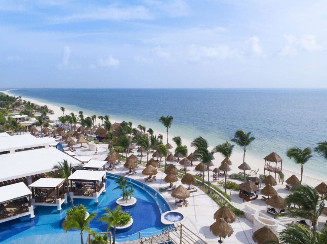 A couple relaxing in a rooftop plunge pool at Excellence Playa Mujeres overlooking the Caribbean Sea at sunset.