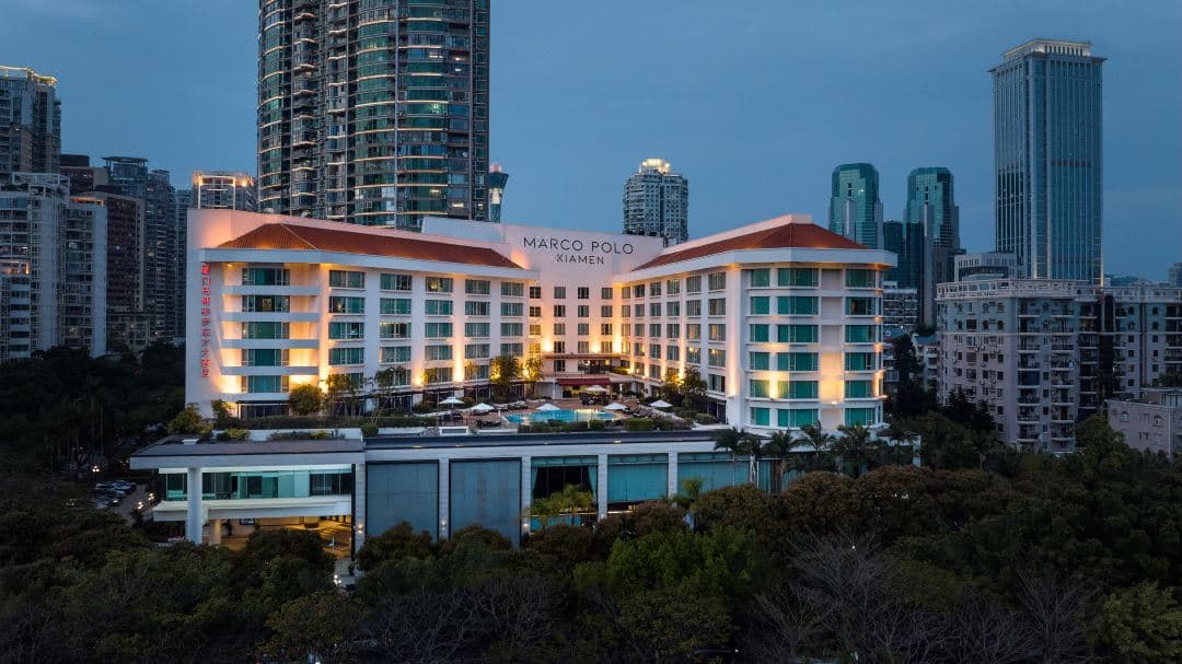 View of Marco Polo Xiamen outdoor pool overlooking Yundang Lake with city skyline in background.