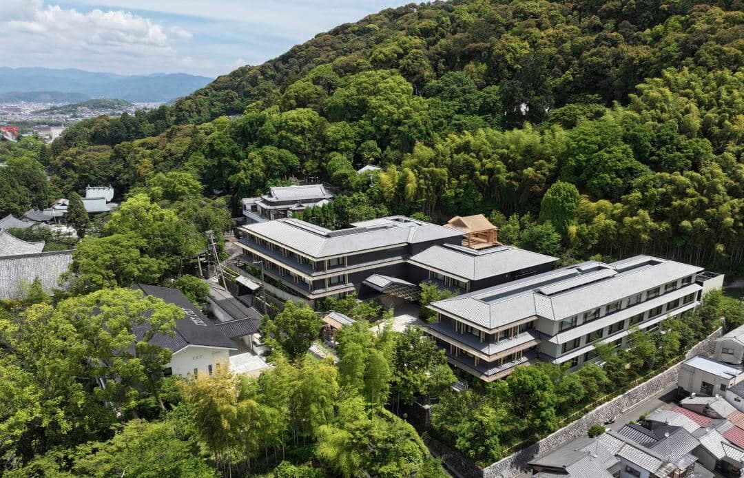 京都东山悦榕庄夜晚灯火通明的能舞台,周围环绕着深色木格栅和竹林。