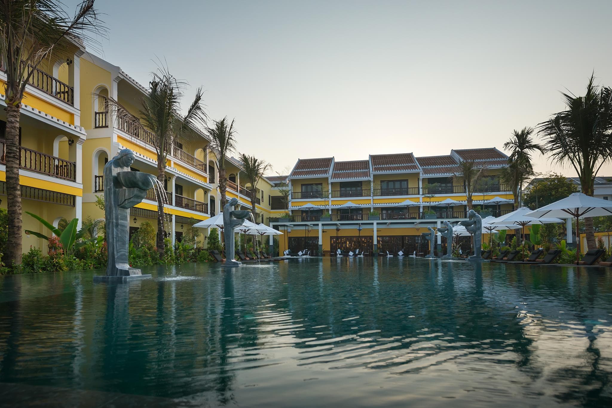 A saltwater infinity pool at La Siesta Hoi An merging visually with vibrant green rice terraces under a soft sunrise.
