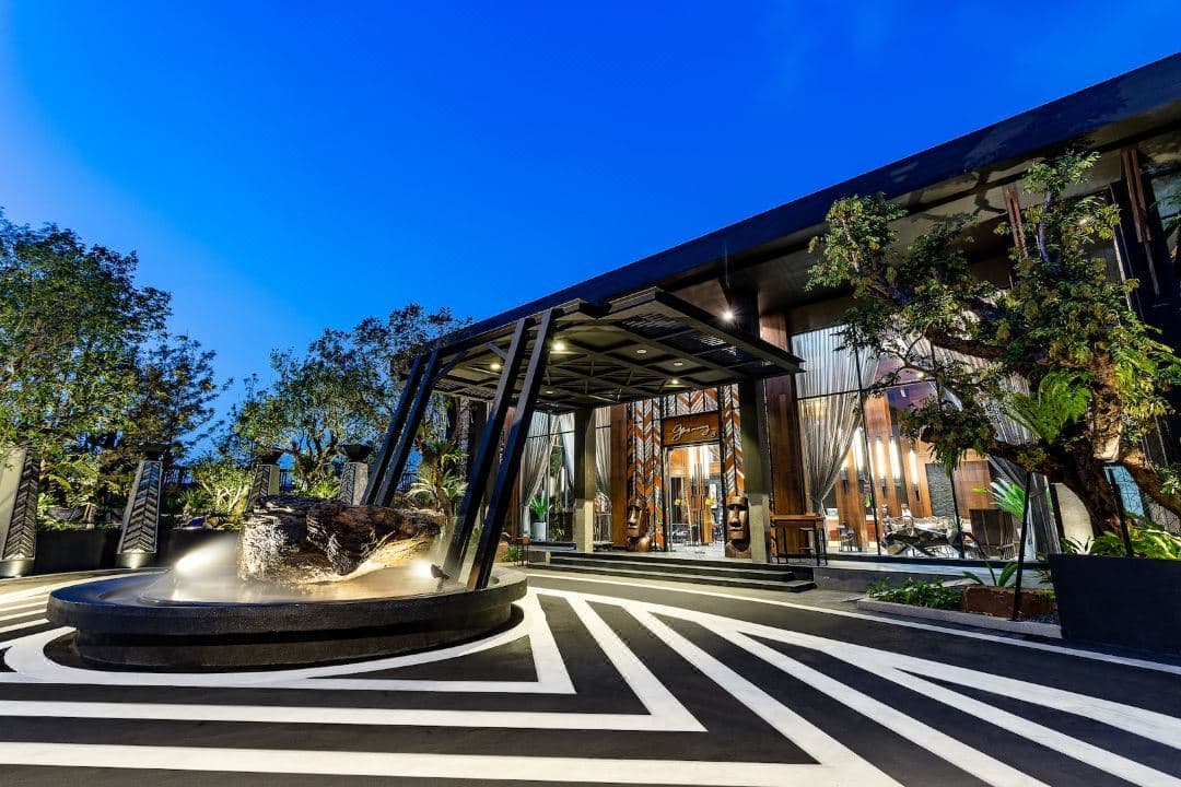 A high-ceilinged Emerald Pool Villa at The Gems Mining Pattaya, featuring industrial-safari decor and a private swimming pool visible through floor-to-ceiling glass doors.