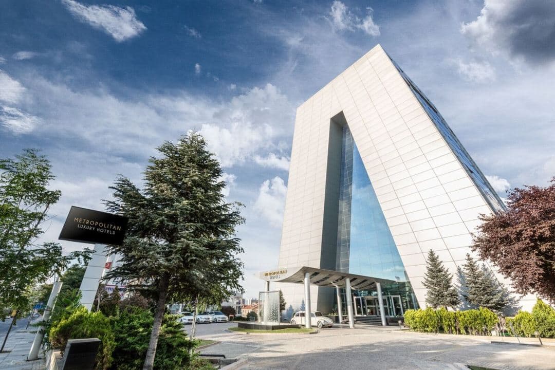 The prismatic glass facade of Metropolitan Hotels Ankara glowing amber at twilight.