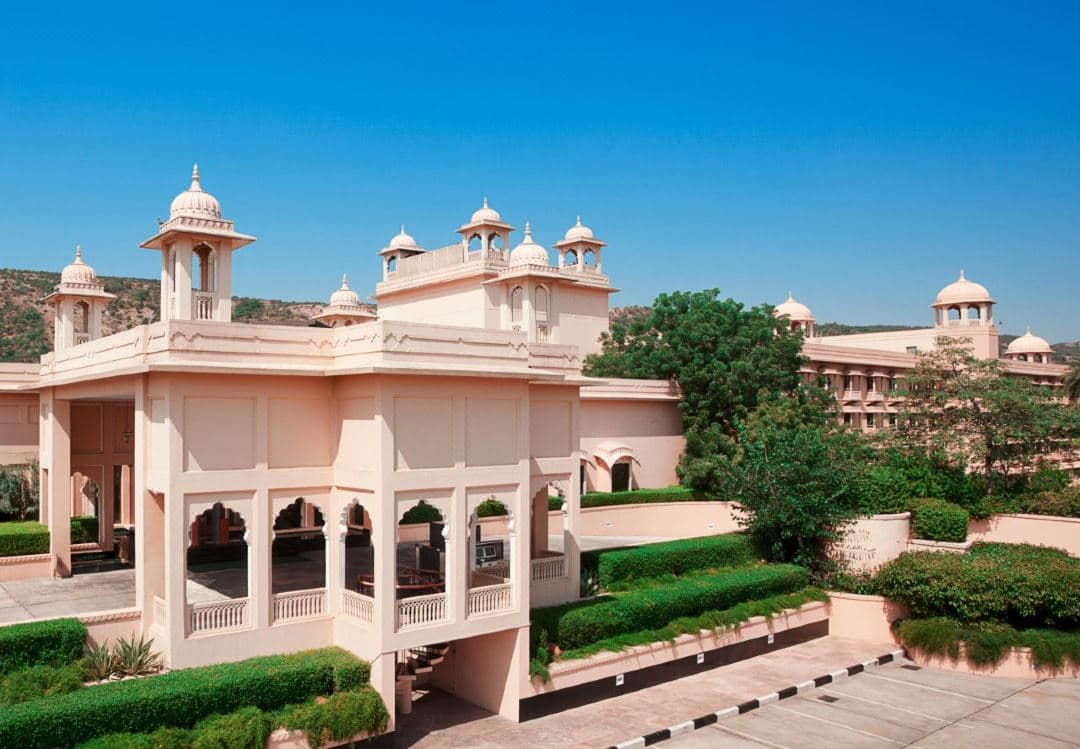 Trident Jaipur pink sandstone facade featuring jharokha balconies overlooking the Aravalli hills.
