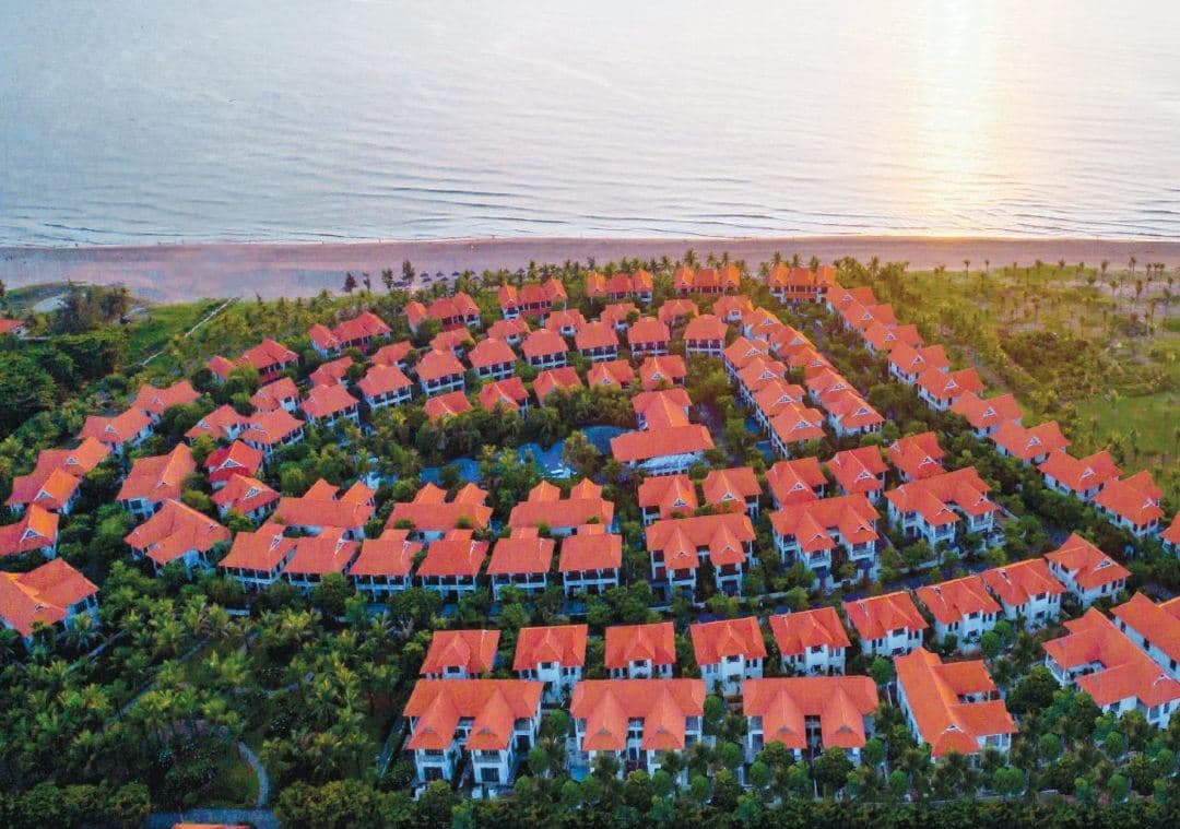 A private pool at Furama Villas Danang surrounded by lush frangipani trees and colonial-style architecture.
