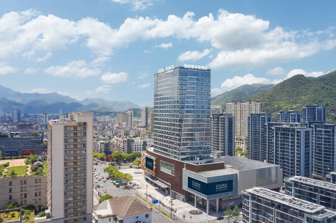 270도 파노라마 시티뷰가 펼쳐지는 통유리창을 갖춘 포포인츠 린하이의 세련된 디럭스 코너 킹 룸의 황혼 무렵 전경.