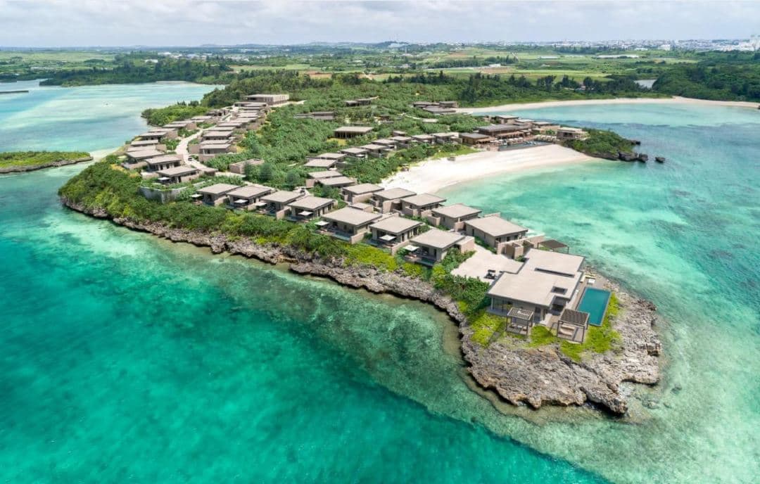 A minimalist limestone villa at Rosewood Miyakojima framing the turquoise Okinawan ocean at sunset.