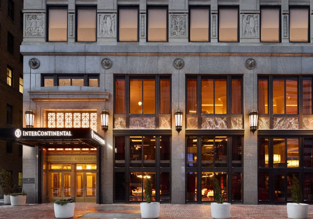 A dramatic low-angle shot of the InterContinental Indianapolis lobby featuring a massive three-story glass chandelier.