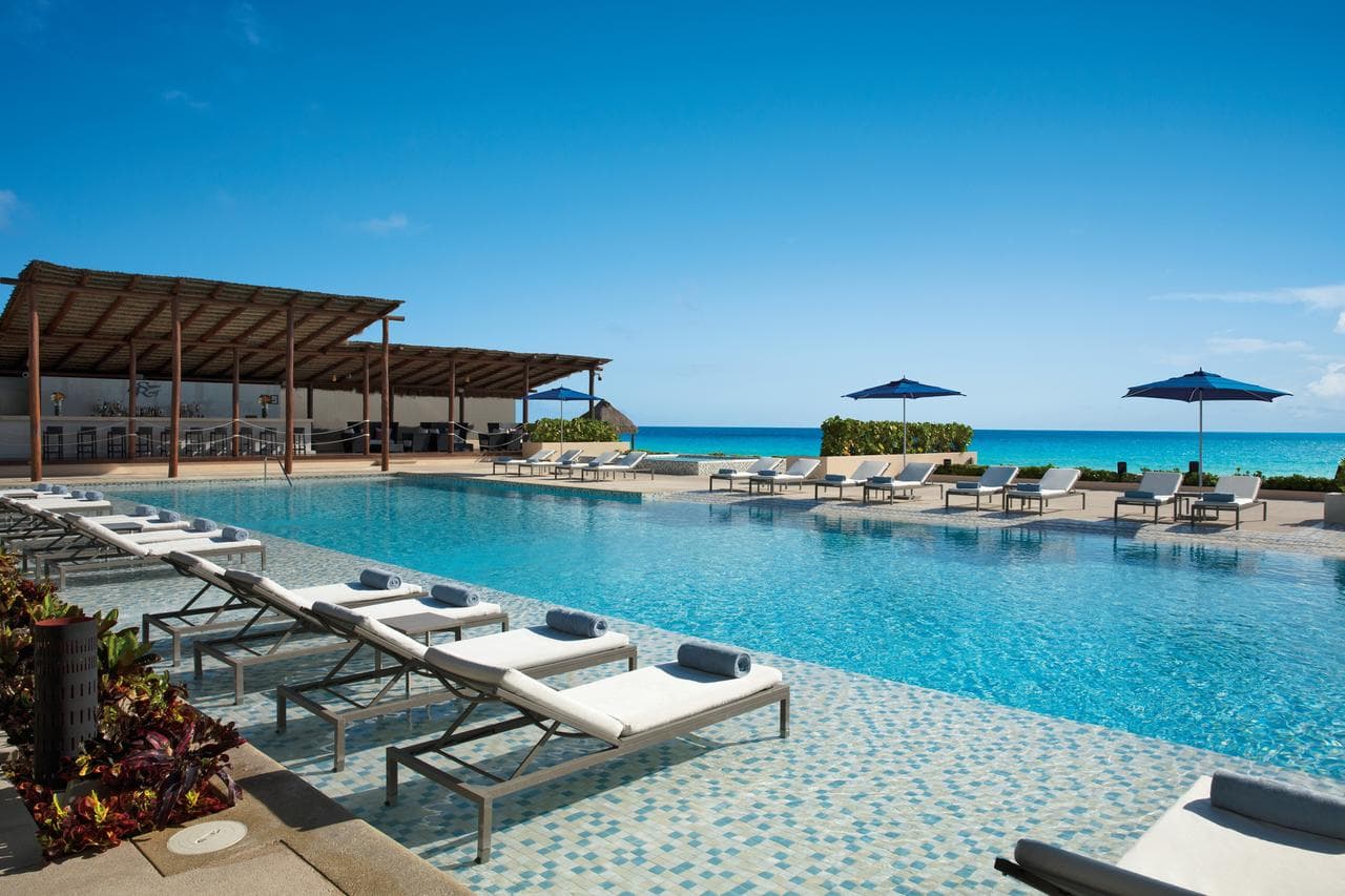 A sleek, modern infinity pool on the 12th floor of Secrets The Vine Cancun overlooking the turquoise ocean.