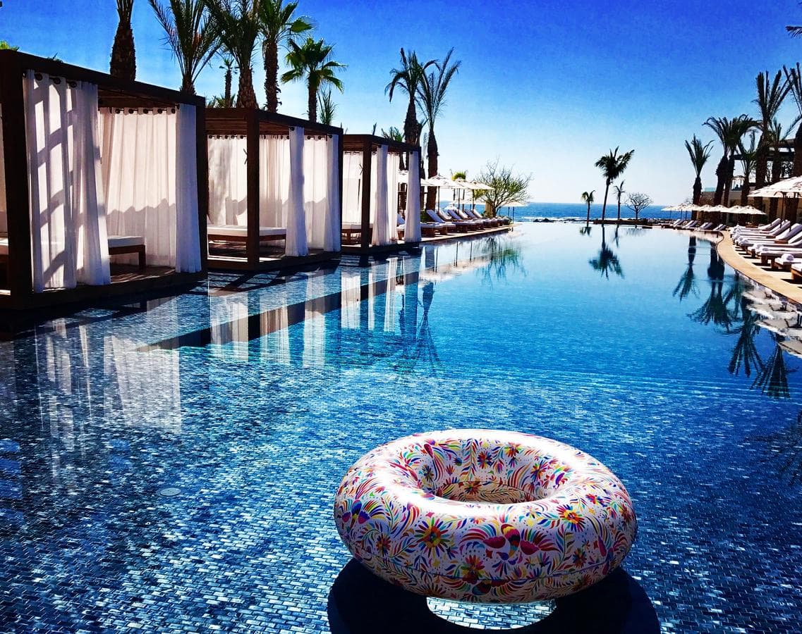 A three-tiered infinity pool at Chileno Bay Resort cascading towards the Sea of Cortez at sunset.