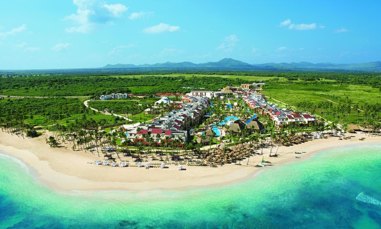 一對情侶在 Breathless Punta Cana 度假村的私人陽台按摩浴缸中享受日落,俯瞰著熱鬧的 Freestyle 派對泳池。