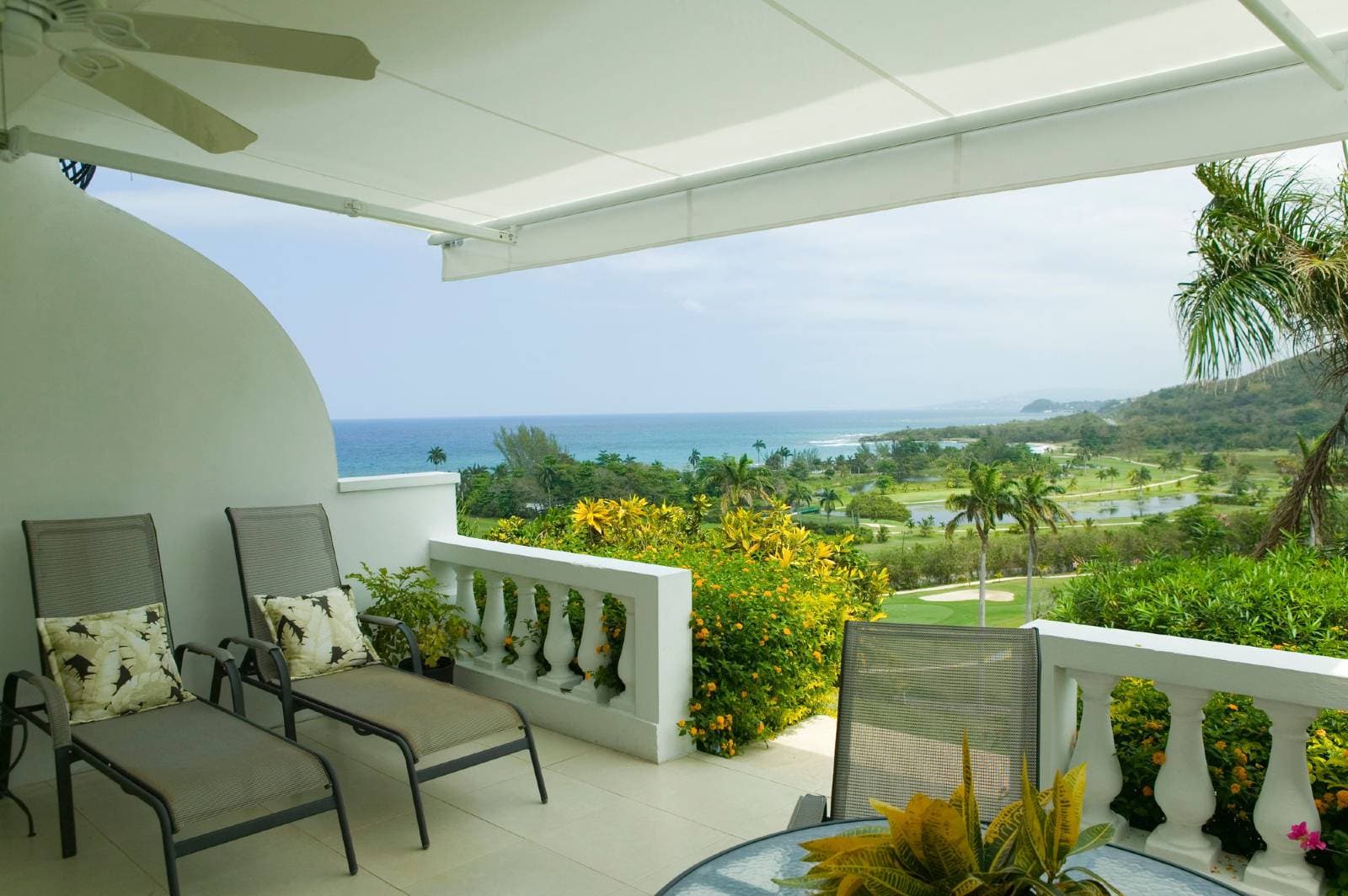 A panoramic view of the 18th-century Waterwheel at The Tryall Club, framed by lush Jamaican greenery and the distant Caribbean Sea.