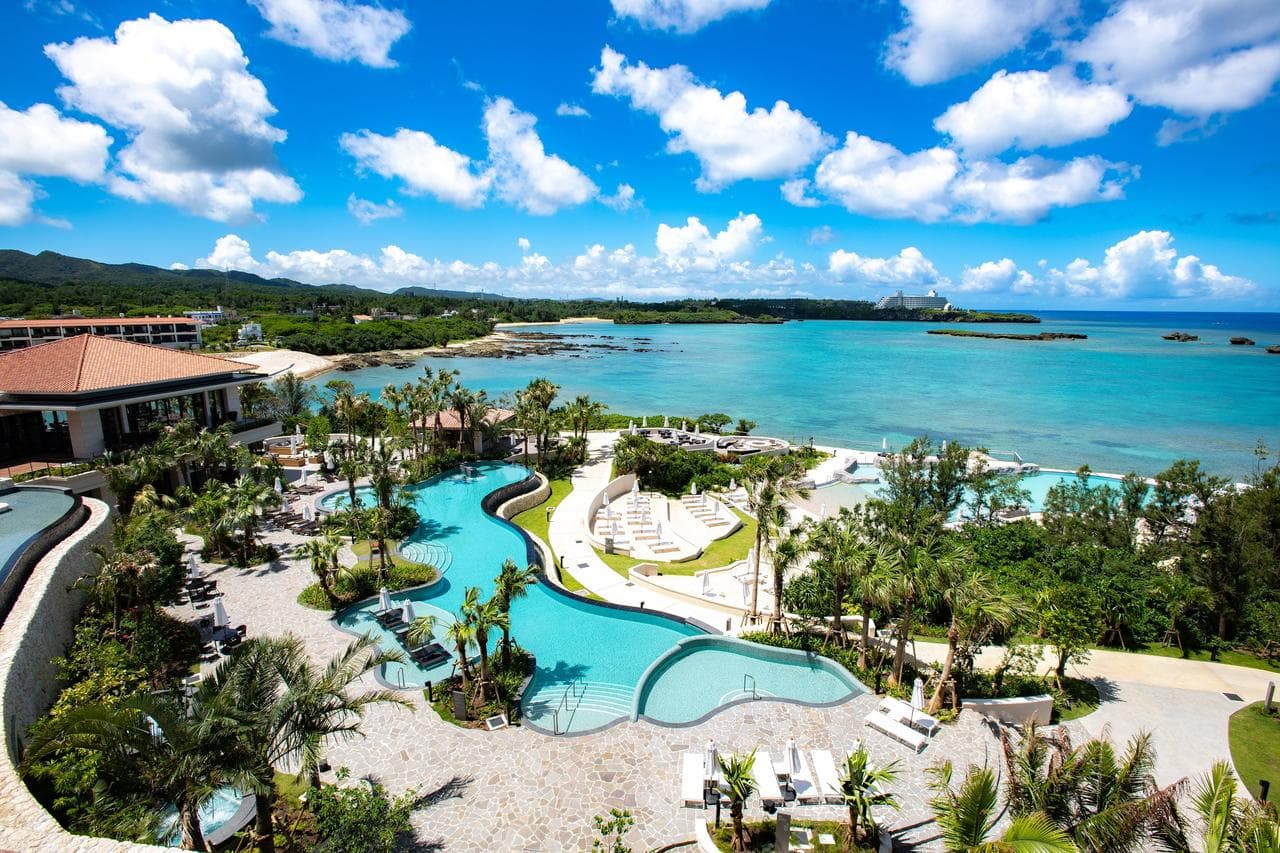 Aerial view of Hyatt Regency Seragaki Island showing the access bridge connecting the small private island to the Okinawa mainland, surrounded by turquoise coral reefs.