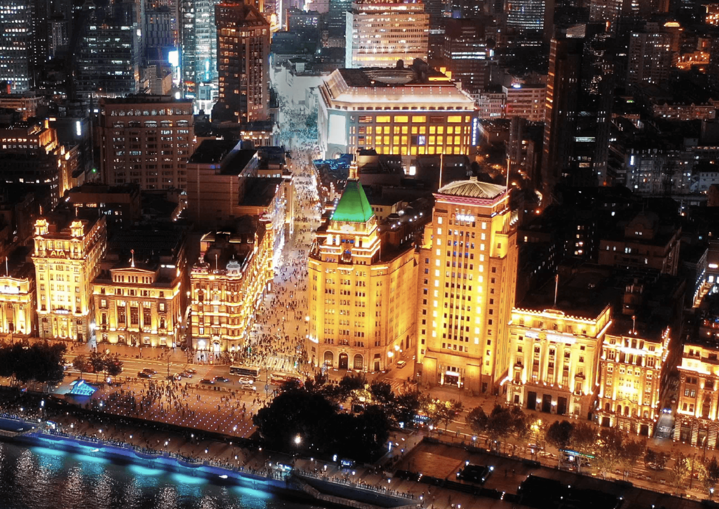 The iconic green copper pyramid roof of the Fairmont Peace Hotel glowing against the futuristic Pudong skyline at twilight.