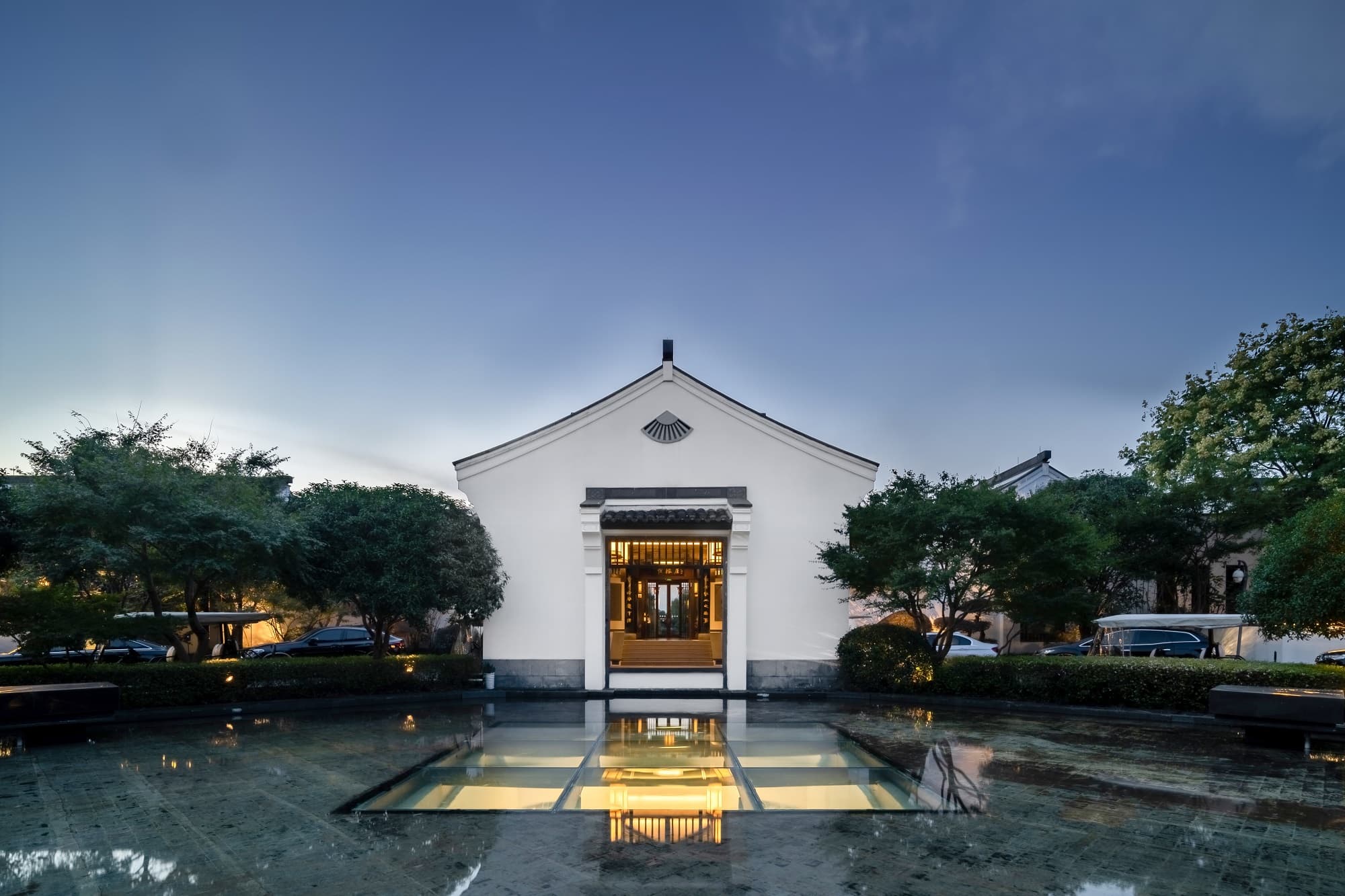 Traditional sculling boat drifting through the Banyan Tree Hangzhou canals at dusk, framed by ivory walls and grey tiled roofs.