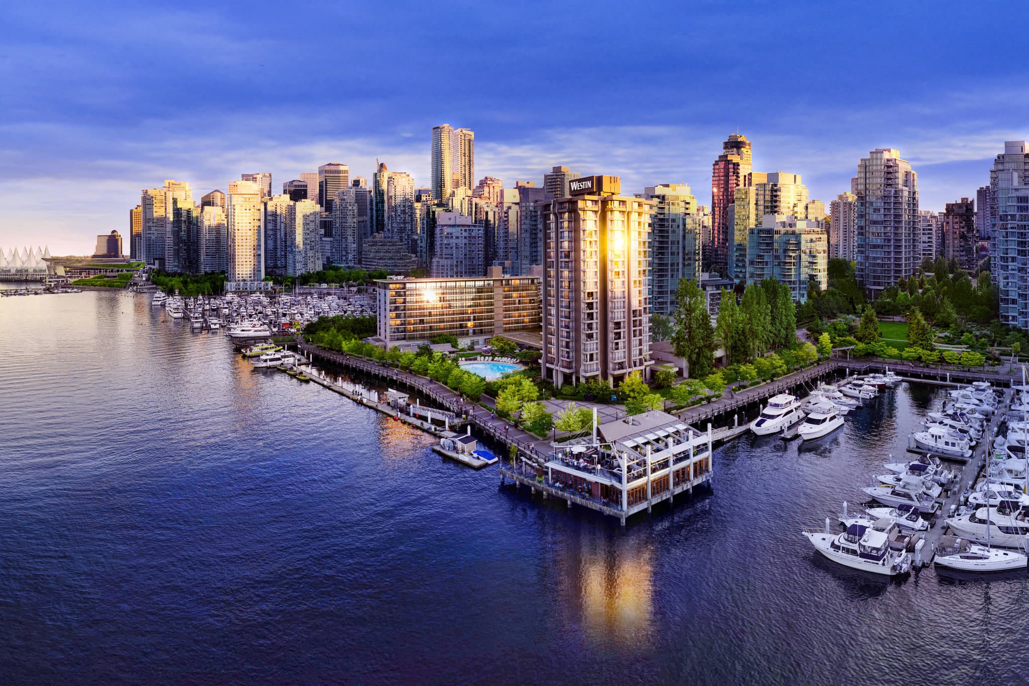 Circular outdoor pool at The Westin Bayshore, Vancouver, with guests lounging near the marina and North Shore mountains in the background.
