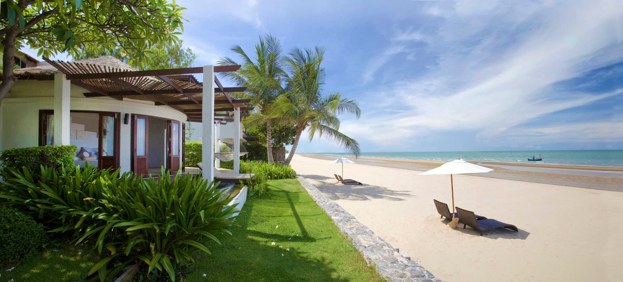 Aleenta Hua Hin infinity pool merging with the Gulf of Thailand at sunrise, framed by thatched-roof villas.