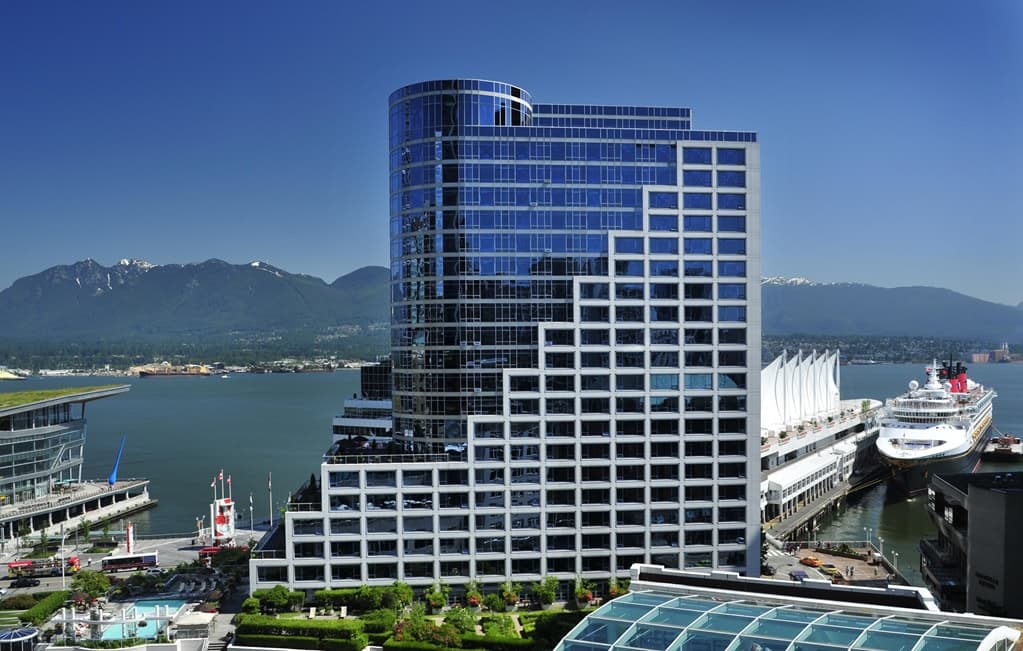 Heated rooftop pool at Fairmont Waterfront Vancouver with steam rising, overlooking the Canada Place sails and North Shore mountains.