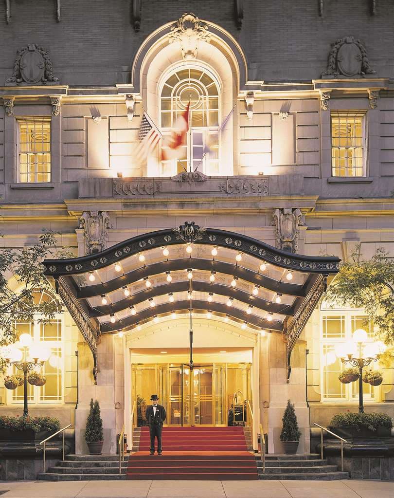 Low angle shot of the Fairmont Palliser's grand lobby featuring marble columns, a gold coffered ceiling, and a vintage fireplace.