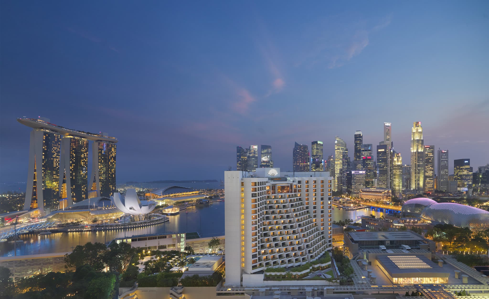 View from Mandarin Oriental Singapore balcony overlooking Marina Bay Sands and the ArtScience Museum at dusk.