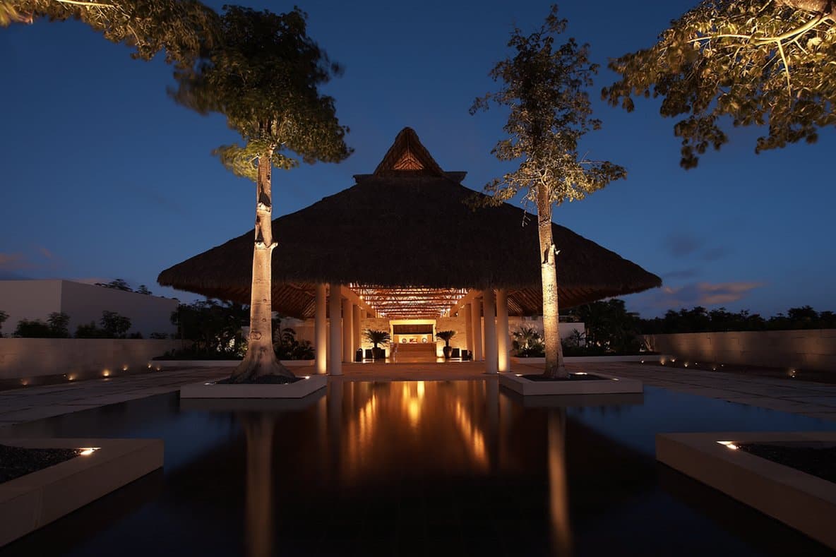 Angular limestone walkways of Blue Diamond Luxury Boutique Hotel cutting through lush green jungle above a mystic cenote water.