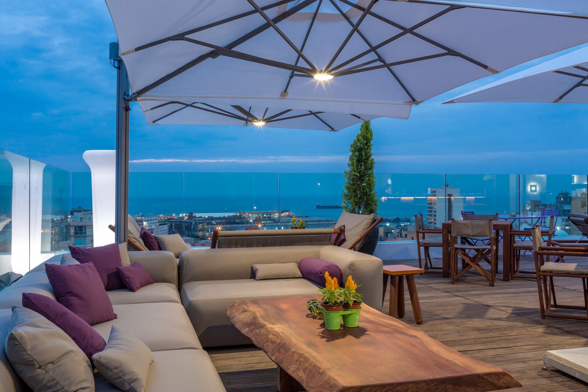 Rooftop pool deck at O Monot Hotel Beirut at dusk with illuminated city skyline in background and modern lounge seating.
