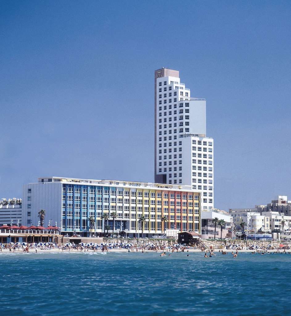 The iconic rainbow-colored facade of the Dan Tel Aviv Hotel towering over the beach promenade.