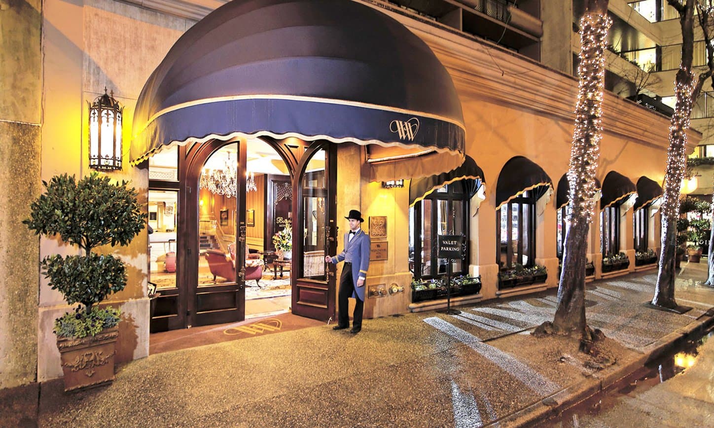 Wedgewood Hotelの「Bacchus Lounge」。落ち着いた木目調の空間に石灰岩の暖炉とベルベットの椅子が配置されている。